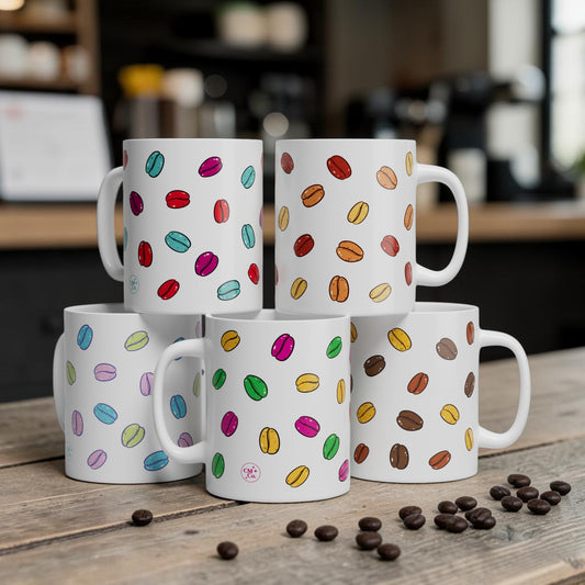 Set of five white mugs with colorful coffee bean patterns on a wooden surface with scattered coffee beans.
