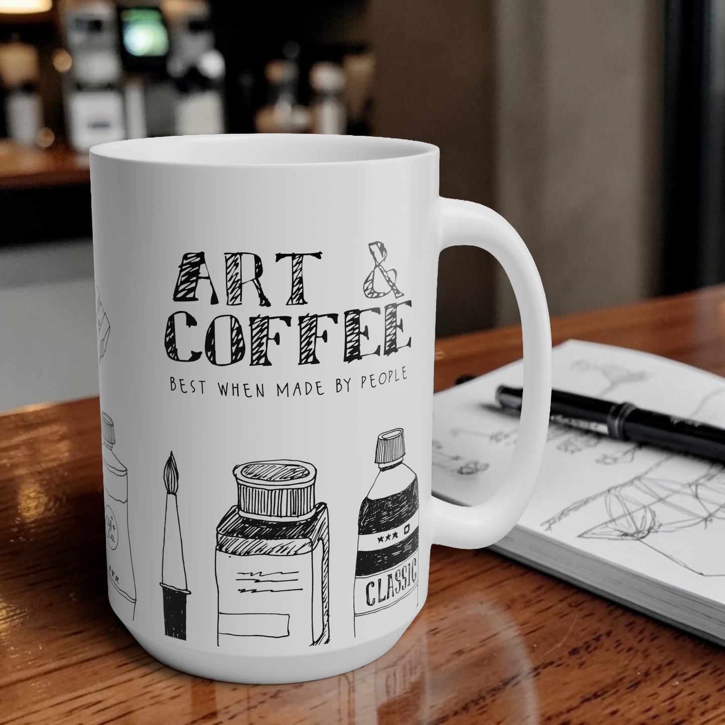 White mug with 'Art & Coffee' design on a wooden table with a blurred coffee shop background