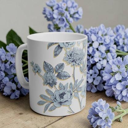 White mug with floral design surrounded by blue flowers on a wooden surface